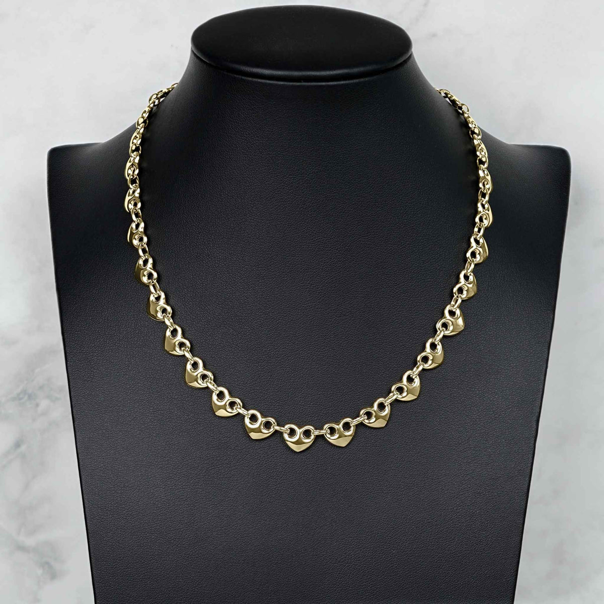 10k gold classic puff heart Gucci link chain necklace displayed on a black jewelry mannequin bust.