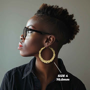 Side profile of a woman wearing 70mm 10k gold heart-themed twisted round hoop earrings.