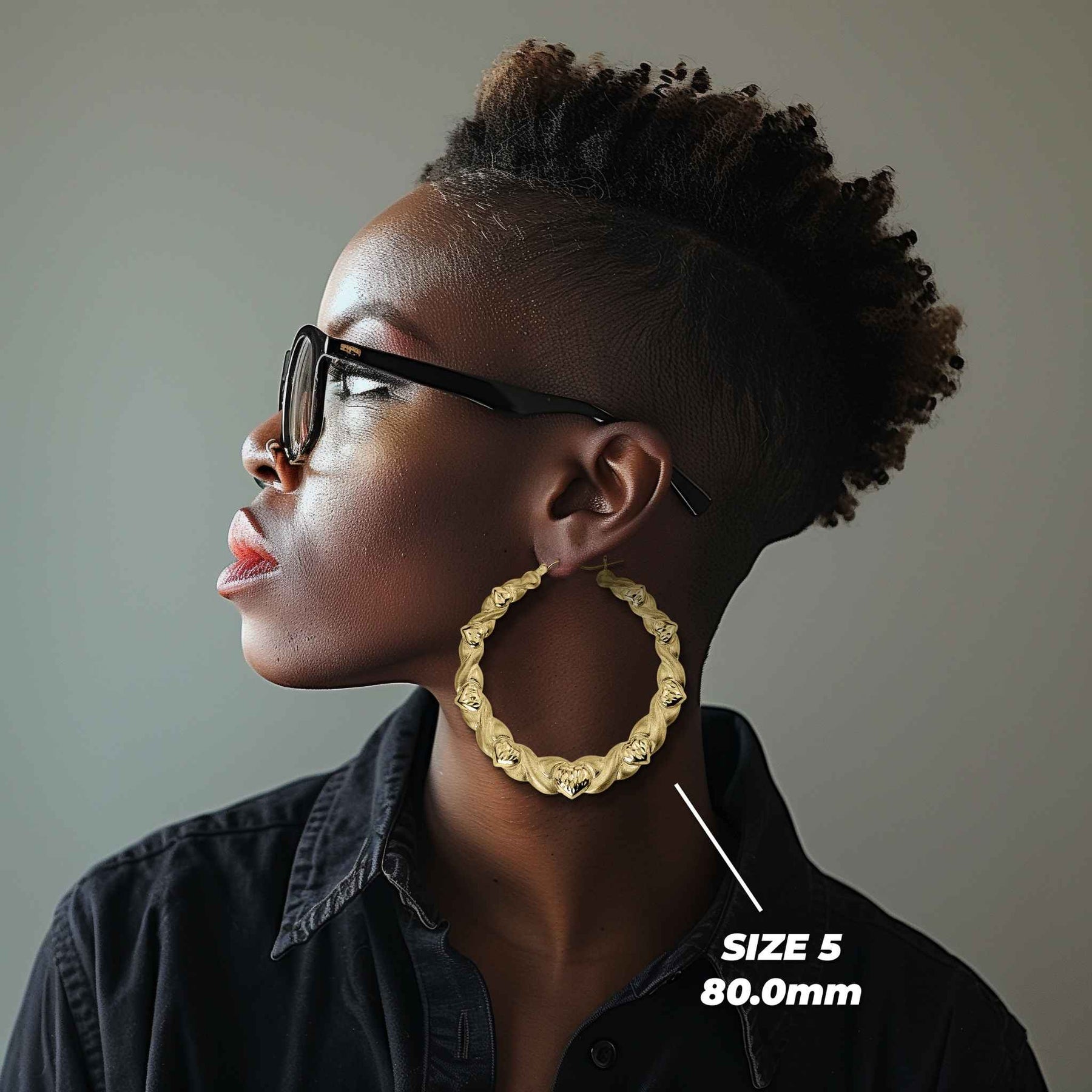 Side profile of a woman wearing 80mm 10k gold heart-themed twisted round hoop earrings.
