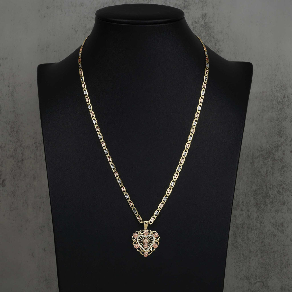 Two-tone San Judas heart pendant on a gold chain, displayed on a black jewelry bust.