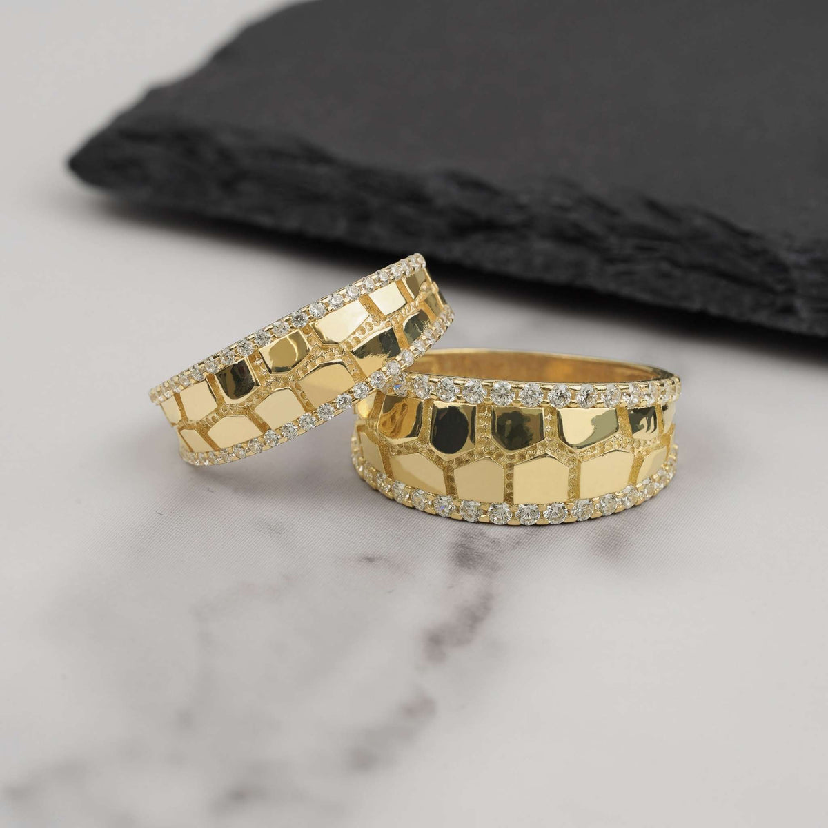 Two gold classic nugget band rings with cubic zirconia edges on marble background.