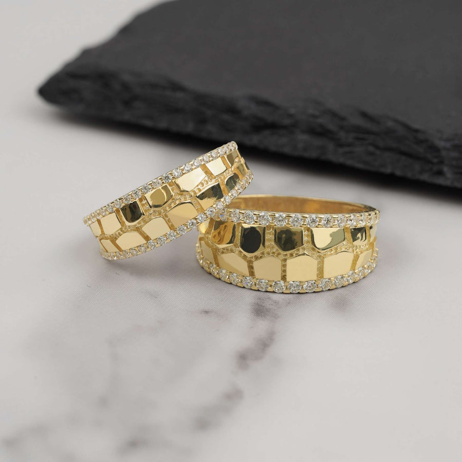 Two gold classic nugget band rings with cubic zirconia edges on marble background.