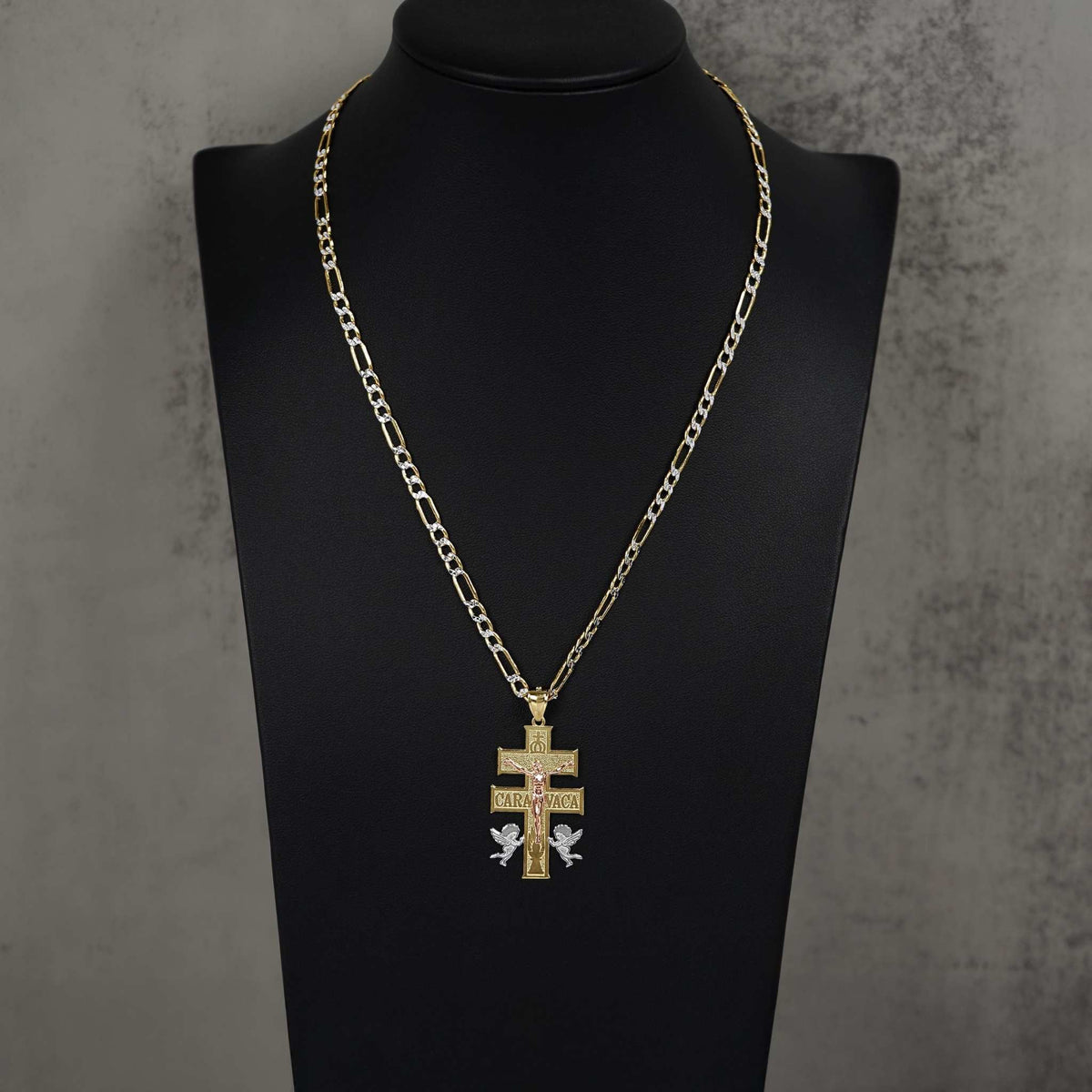 Tri-color gold Caravaca cross pendant necklace on figaro chain displayed on a mannequin bust.