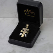 Tri-color gold Caravaca cross pendant presented inside an open black velvet jewelry box.