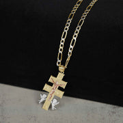 Tri-color gold Caravaca crucifix pendant with angel details, displayed on a Figaro link chain.