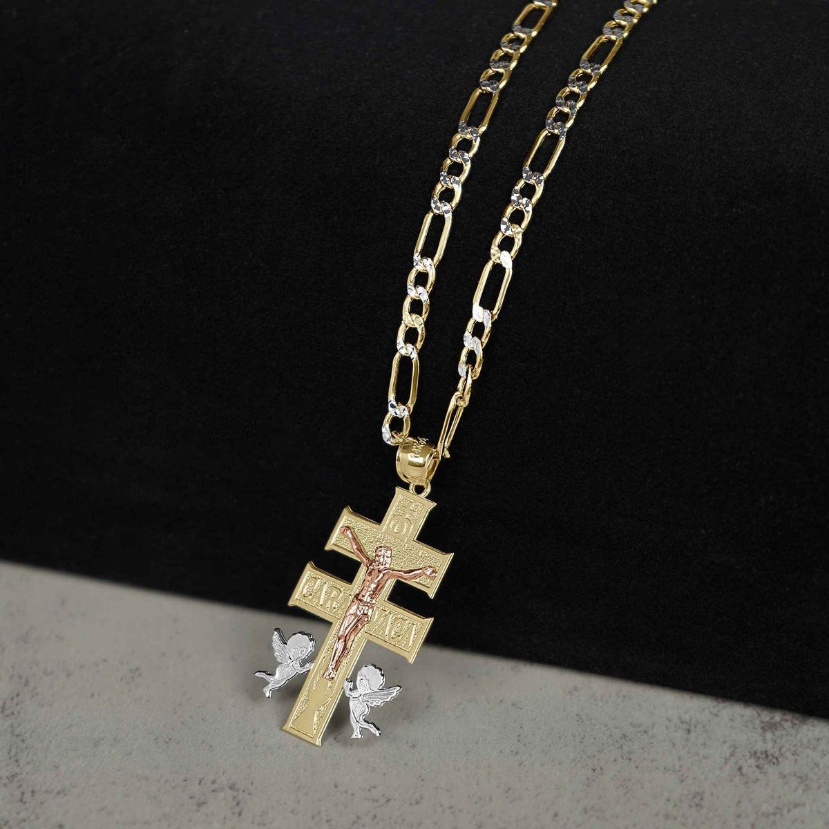 Tri-color gold Caravaca crucifix pendant with angel details, displayed on a Figaro link chain.