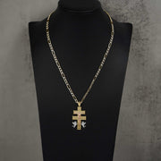 Gold Caravaca cross pendant on a Figaro chain, displayed on a black jewelry bust.