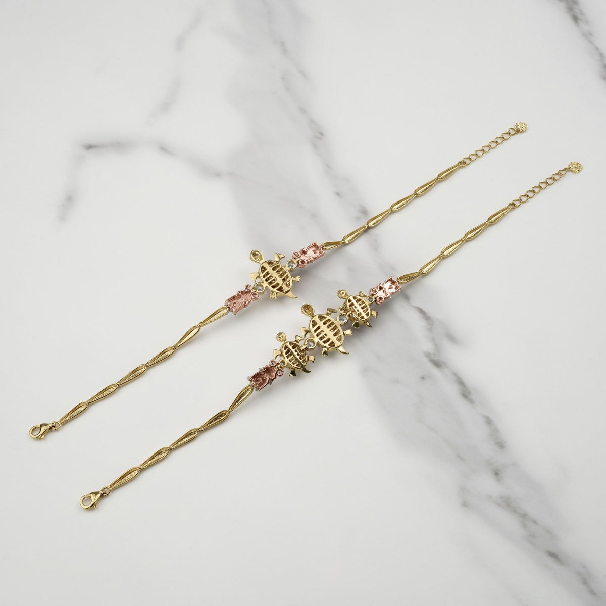 Reverse side of gold Cari turtle bracelets showing the hollow back design on marble.