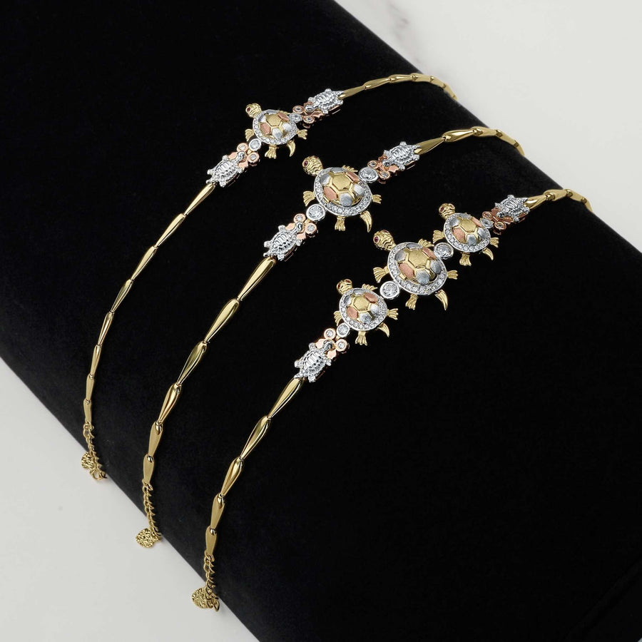 Tricolor gold turtle bracelets adorned with sparkling CZ stones on a black display.