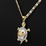 Tricolor gold turtle pendant necklace featuring a patterned shell and red gemstone eyes.