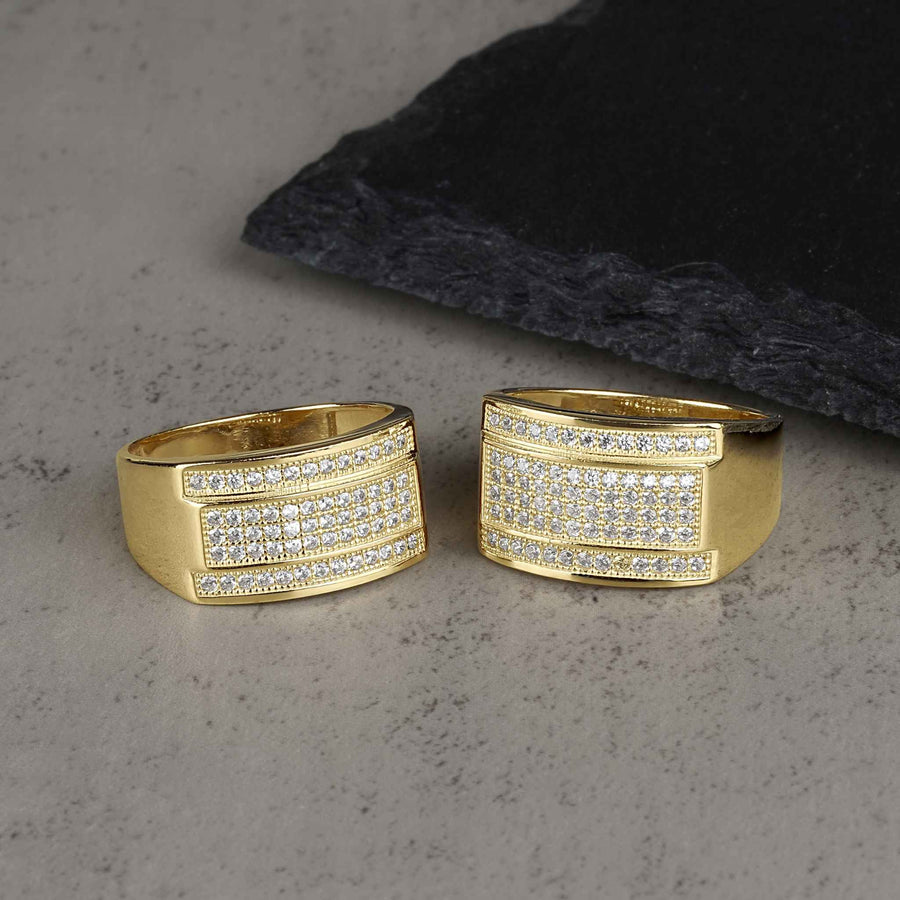 Close-up of two yellow gold band rings fully paved with rows of glistening crystals.