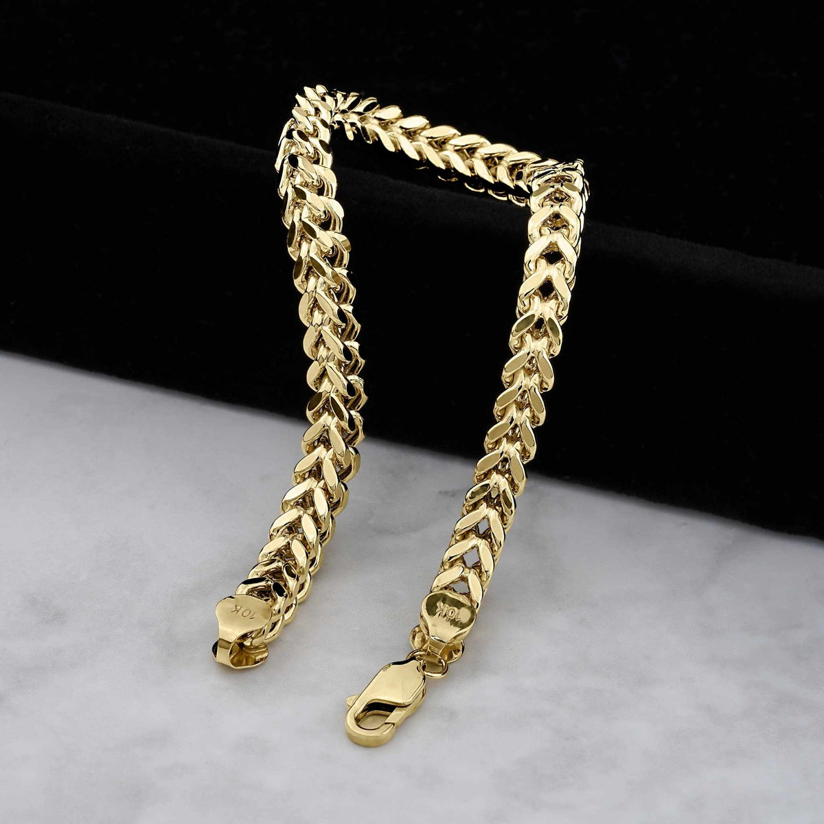 Detailed view of polished yellow gold Franco link chain bracelets with lobster clasps