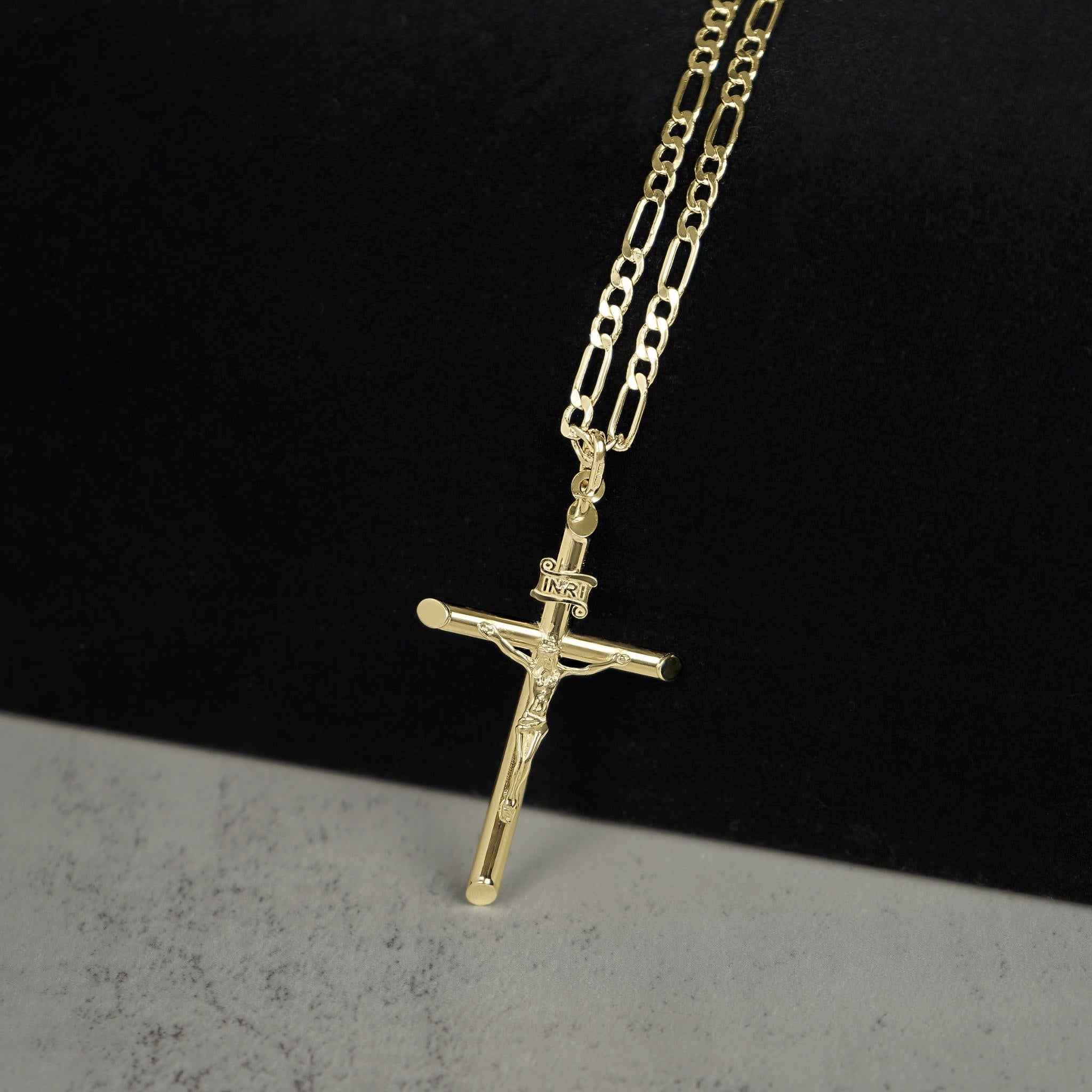 Yellow gold INRI crucifix cross pendant attached to a gold Figaro chain.
