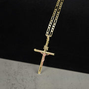 Two-tone gold INRI crucifix pendant hanging on a Figaro chain.