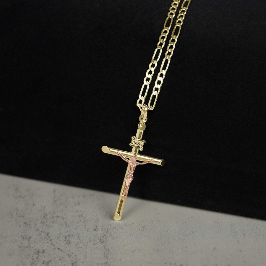 Two-tone gold INRI crucifix pendant hanging on a Figaro chain.