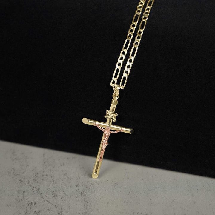 A gold and rose gold crucifix pendant necklace on a paperclip chain against a dark background.