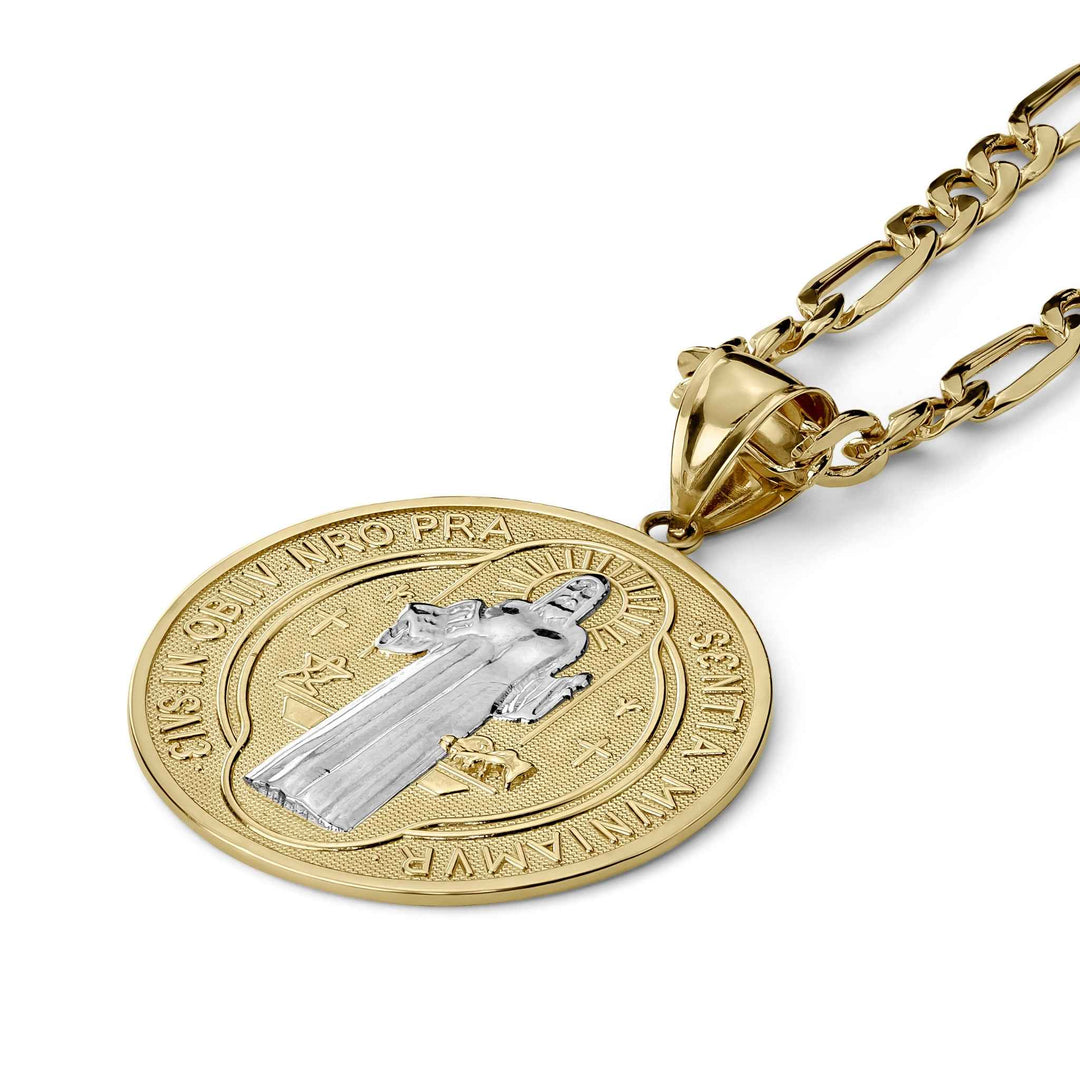 Close-up of a two-tone gold Saint Benedict medal pendant on a matching chain against white.