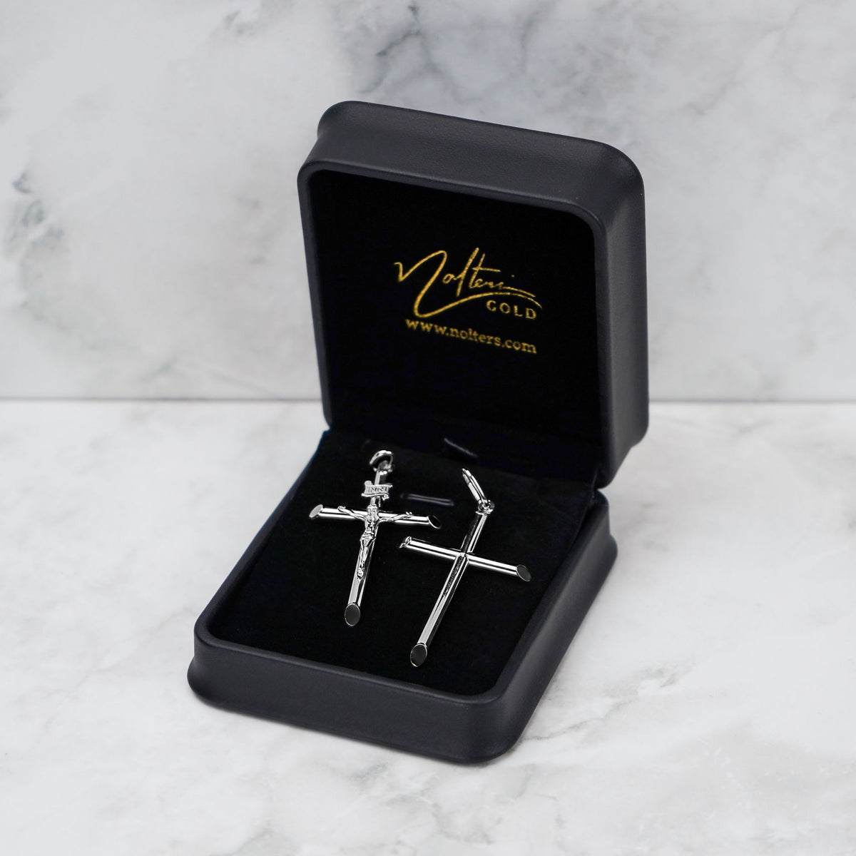White gold tube cross pendant in a black Nolters box on marble.