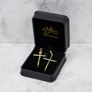 Yellow gold tube cross pendant in a black Nolters box on white marble.