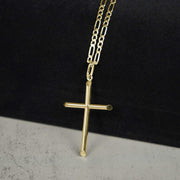 Yellow gold tube cross pendant necklace on a paperclip chain against a two-tone background.