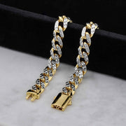 Close-up of gold DC Monaco Miami Cuban chain bracelets on display surface.