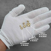 A gloved hand displays three different sizes of gold hibiscus flower pendants with dimension labels.