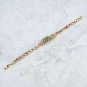 Tricolor gold Quinceañera leaf bracelet displayed diagonally on white marble.