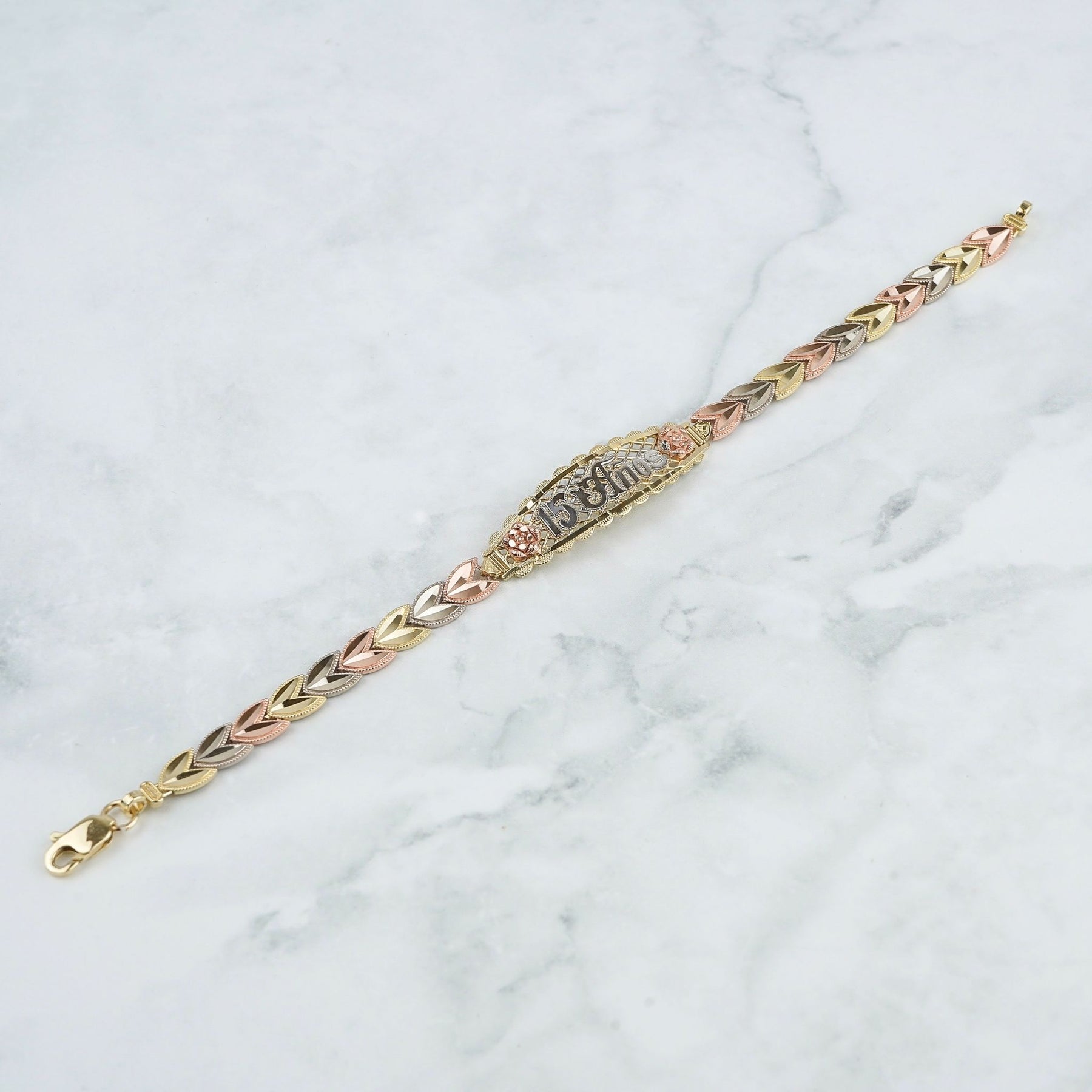 Tricolor gold Quinceañera leaf bracelet displayed diagonally on white marble.