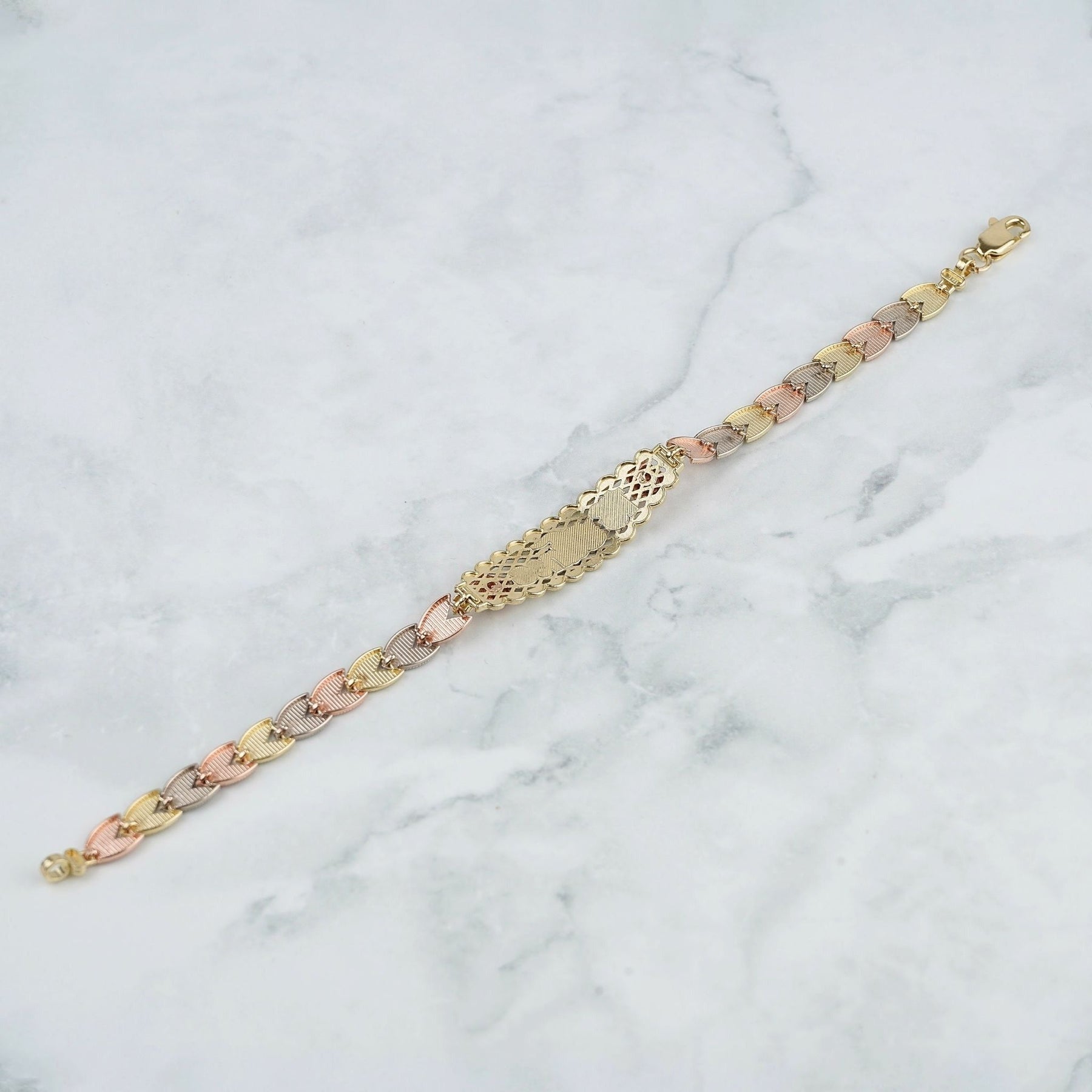 Back view of a tricolor gold quinceañera leaf bracelet resting on white marble.
