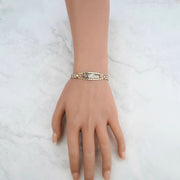 Tri-color gold quinceañera leaf bracelet displayed on a mannequin hand against marble.