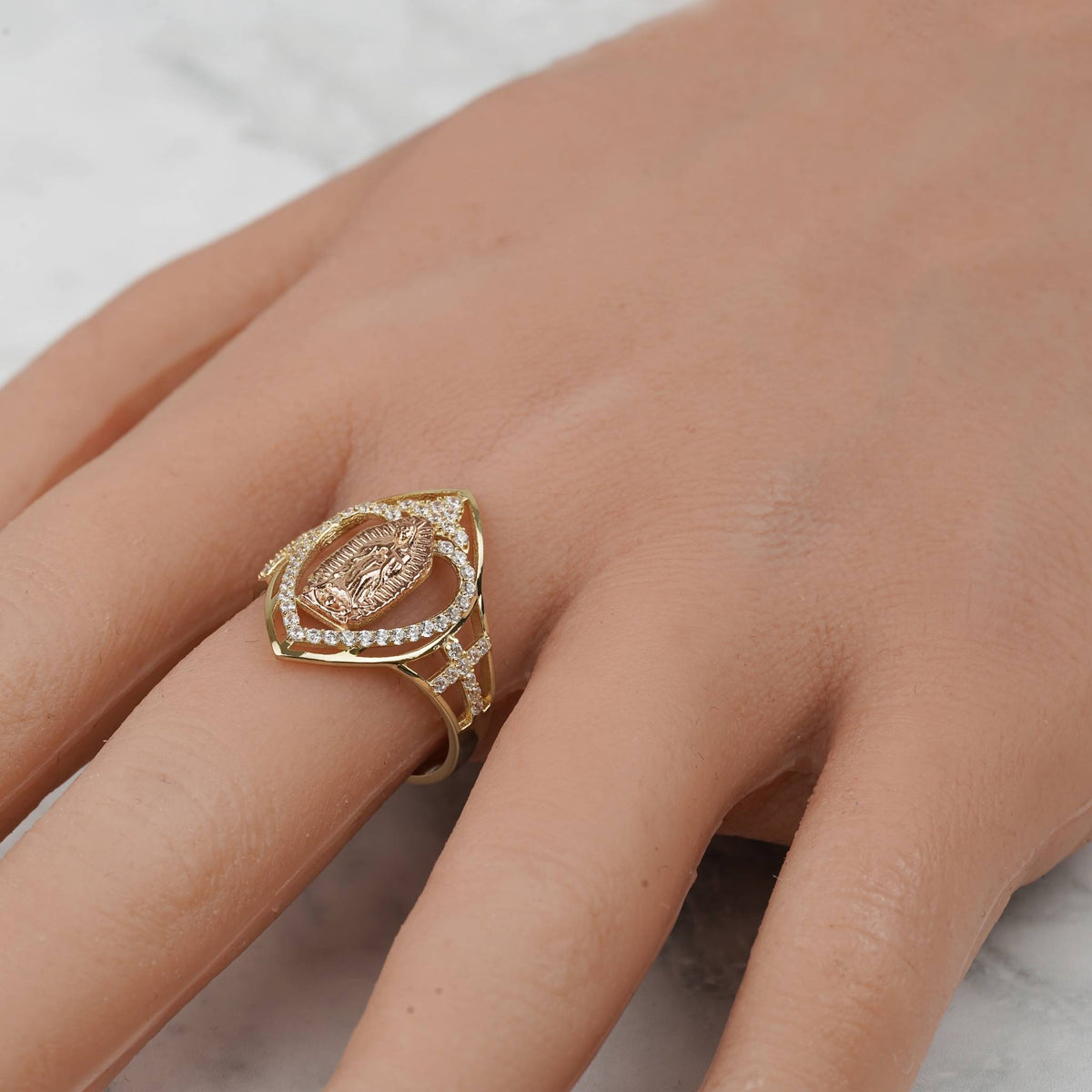 Close-up of the 10k and 14k gold marquise Virgin Mary ring worn on a finger.