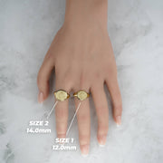 Lifestyle hand view of two gold Aztec Mayan calendar round rings with millimeter labels.