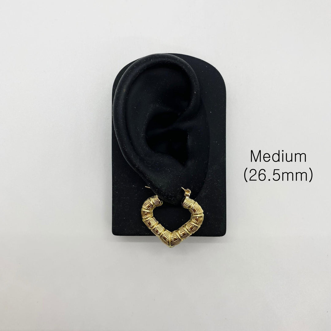 Medium 26.5mm gold bamboo heart hoop earring displayed on a black ear model.