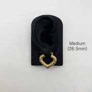Medium 26.5mm gold bamboo heart hoop earring displayed on a black ear model.