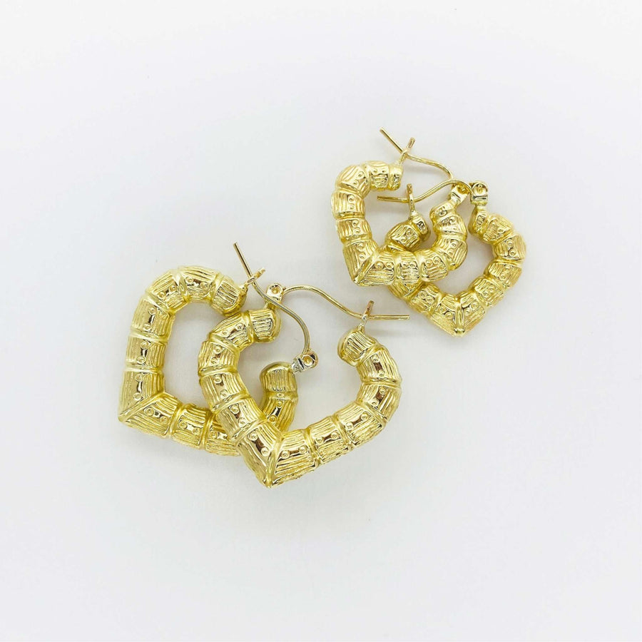 Two pairs of textured gold bamboo heart-shaped hoop earrings on a white background.