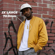 A man wearing a white cap and yellow jacket features an extra-large gold hundred-dollar bill necklace.