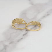Back view of two gold dual heart rings showing textured finish on white marble surface