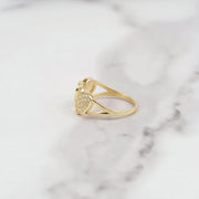 Side profile view of gold dual heart ring with pavé white CZ stones on white marble surface