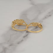 Back view of two gold dual-heart cubic zirconia rings on white marble.