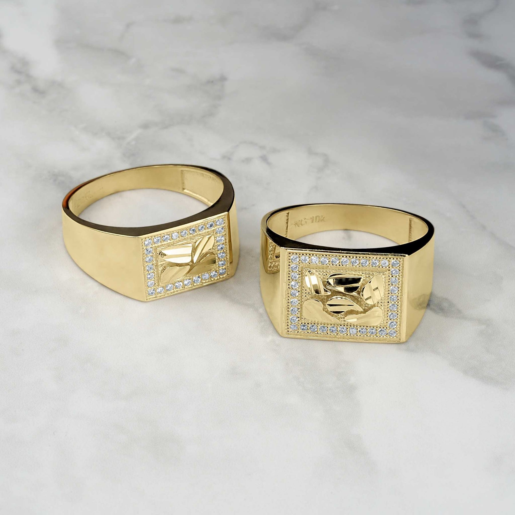 Two gold rectangle nugget rings with cubic zirconia borders on a marble surface.