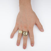 Top-down view of a hand wearing a cannabis leaf ring and a coin signet ring.