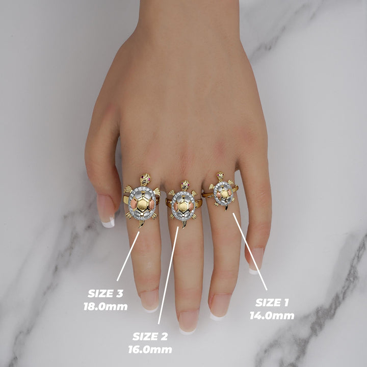 Three tricolor gold Cari turtle rings worn on a hand showing Size 1, 2, and 3.