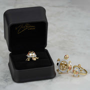 Tricolor gold turtle rings displayed inside and next to a black Nolters jewelry box.