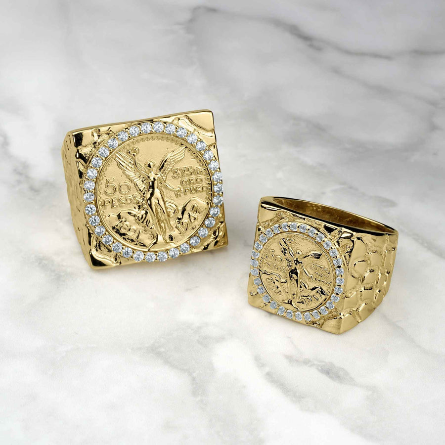 Yellow gold Centenario 50 Pesos coin rings with cubic zirconia borders on marble.