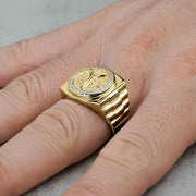 Close-up of men's gold Centenario pesos ring with cubic zirconia border on a hand.