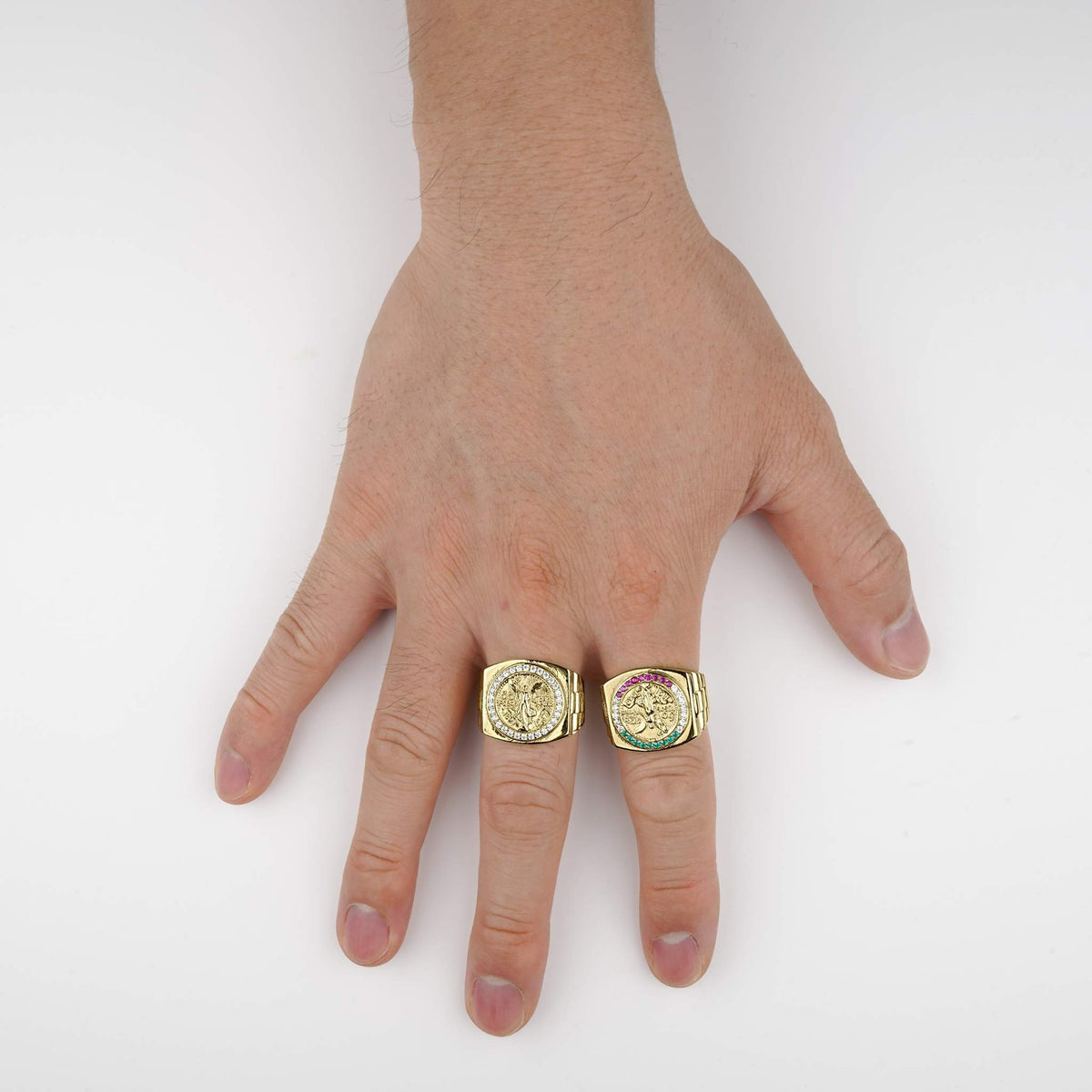 Hand wearing two gold Centenario pesos ring with different design on a white background.