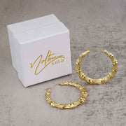 Gold bamboo-design round hoop earrings and a Nolters Gold jewelry box.