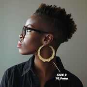 Side profile of a woman wearing 76mm 10k gold classic bamboo round hoop earrings.
