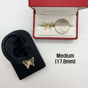 Gold butterfly earring on a black ear model with a medium-sized version shown for scale.