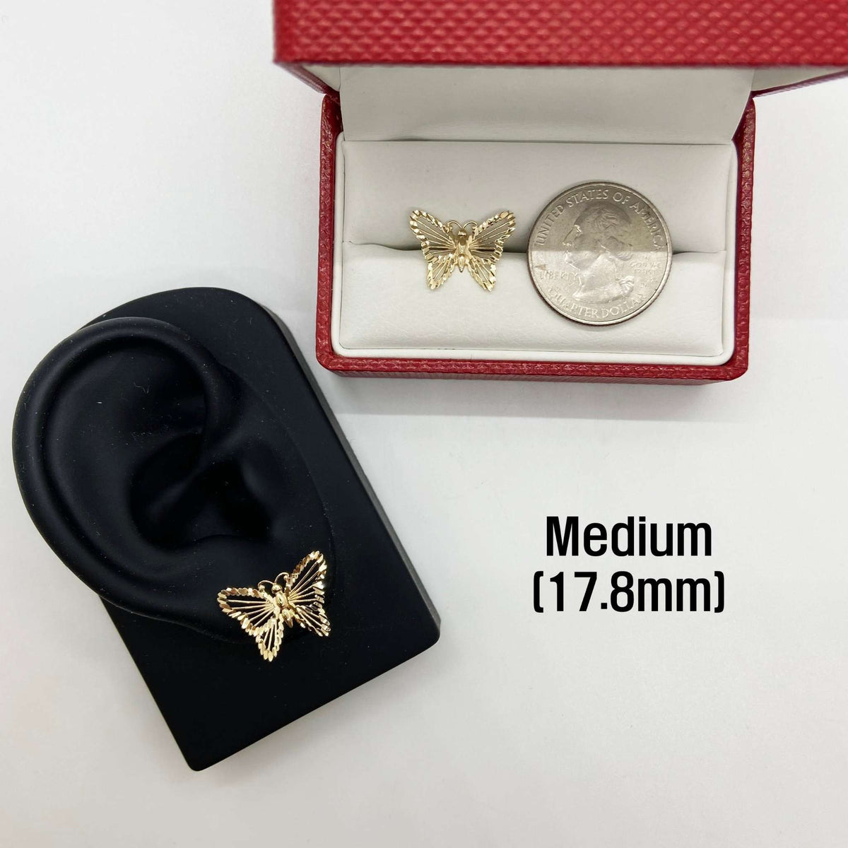 Gold butterfly earring on a black ear model with a medium-sized version shown for scale.